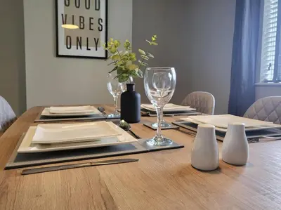 a wooden table with plates and wine glasses on it at Jersey Cottage in Horseheath