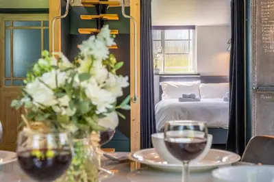 a table with a vase of flowers and two glasses of wine at Ultimate Constable Country rural retreat - The Pump House in Colchester