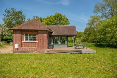a small brick house with a table on a deck at Ultimate Constable Country rural retreat - The Pump House in Colchester