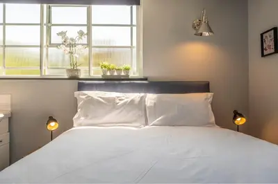 a bedroom with a bed with white pillows and two windows at Ultimate Constable Country rural retreat - The Pump House in Colchester