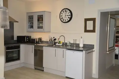 a kitchen with white cabinets and a clock on the wall at The Mill B&B in Thetford