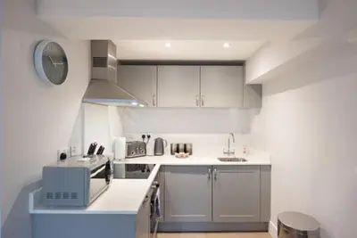 a small kitchen with white cabinets and a sink at S/KING BED ONE BEDROOM FLAT in Brentwood