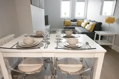 a white table with plates and glasses on it in a living room at S/KING BED ONE BEDROOM FLAT in Brentwood