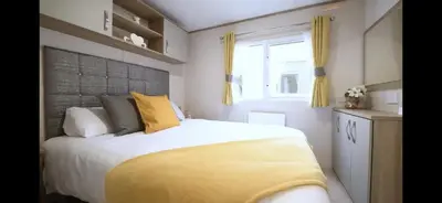 a bedroom with a large bed and a window at Coopers Beach 3-Bed Caravan Sleeps 8 & Pets Ok in Colchester