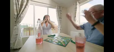 an older man and a woman sitting at a table at Coopers Beach 3-Bed Caravan Sleeps 8 & Pets Ok in Colchester