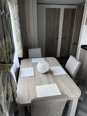 a dining room table with two chairs and a wooden table at Coopers Beach 3-Bed Caravan Sleeps 8 & Pets Ok in Colchester