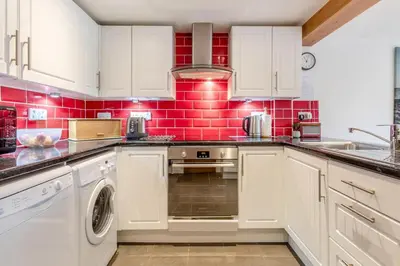 a kitchen with white cabinets and red tiles at 3 Bed in Middleton oc-fdp in Middleton