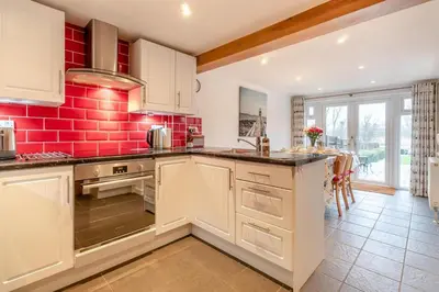 a kitchen with white cabinets and a red brick wall at 3 Bed in Middleton oc-fdp in Middleton