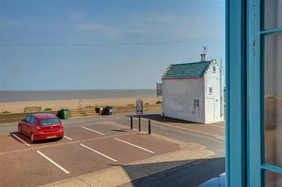 a red car parked in a parking lot near the beach at 3 Bed in Aldeburgh oc-marg in Aldeburgh
