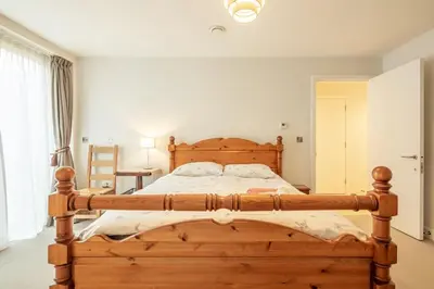 a bedroom with a wooden bed in a room at Luxury Ensuite Room 2 Minutes from Cambridge Station in Cambridge