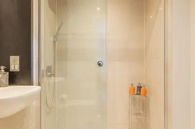 a shower with a glass door next to a sink at Luxury Ensuite Room 2 Minutes from Cambridge Station in Cambridge