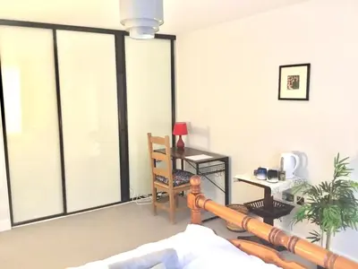 a living room with a large window with a table at Luxury Ensuite Room 2 Minutes from Cambridge Station in Cambridge