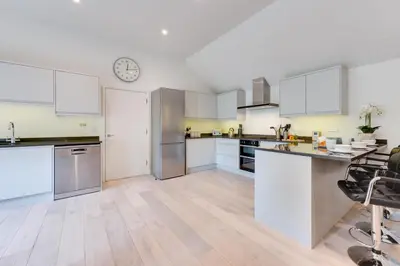 a kitchen with white cabinets and a clock on the wall at 3 Bed in Snape oc-1wadd in Snape