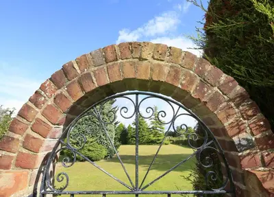 an iron gate with a garden behind it at 3 Bed in Aldeburgh oc-10nw in Aldeburgh