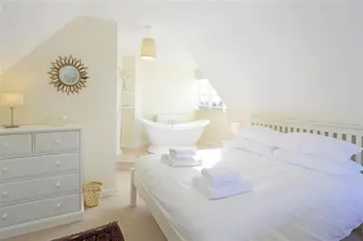 a white bedroom with a white bed and a bath tub at 5 Bed in Thorpeness oc-whin2 in Thorpeness