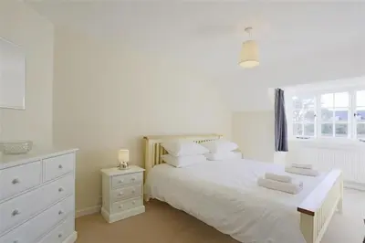 a white bedroom with a white bed and a window at 5 Bed in Thorpeness oc-whin2 in Thorpeness
