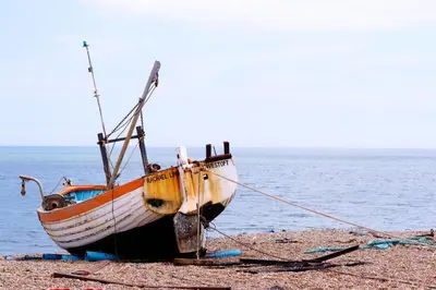 a boat sitting on the beach next to the water at 2 Bed in Aldeburgh oc-3al in Aldeburgh