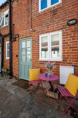 two chairs and a table in front of a brick building at 2 Bed in Aldeburgh oc-3al in Aldeburgh