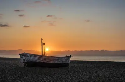 a boat sitting on the beach at sunset at 2 Bed in Aldeburgh oc-3al in Aldeburgh
