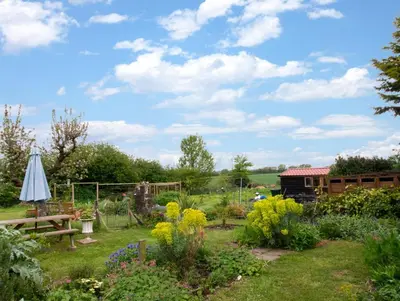 a garden with a table and a umbrella and flowers at 2 Bed in Long Melford oc-9ws in Long Melford