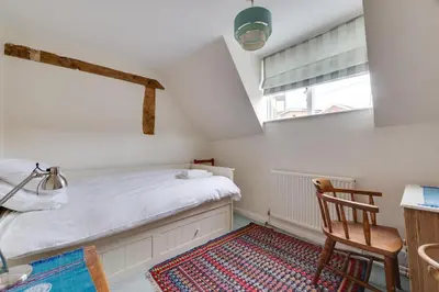 a small attic bedroom with a bed and a chair at 3 Bed in Woodbridge oc-acot in Woodbridge