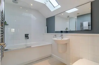 a bathroom with a sink and a tub and a mirror at 3 Bed in Knodishall oc-ebco in Aldringham