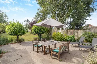 a patio with a wooden table and an umbrella at 3 Bed in Westleton Saxmundham oc-est in Westleton