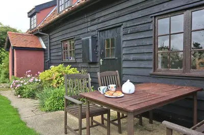 a wooden table with a plate of food on it next to a house at 3 Bed in Hemley oc-g91 in Hemley