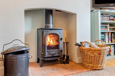 a wood burning stove in a room with a basket at 2 Bed in Aldeburgh oc-fsh in Aldeburgh