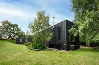 a black house in a field with trees at 3 Bed in Bramfield oc-hglenv in Bramfield
