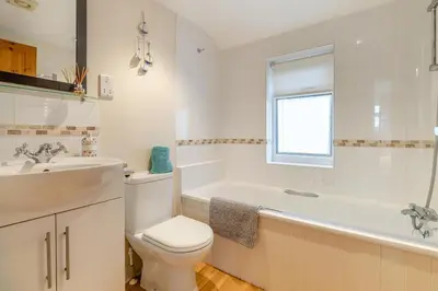 a bathroom with a toilet and a tub and a sink at 3 Bed in Middleton oc-htv in Middleton