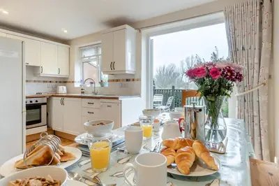 a kitchen with a table with croissants and flowers at 3 Bed in Middleton oc-htv in Middleton