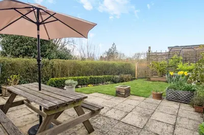 a wooden picnic table with an umbrella in a garden at 2 Bed in Halesworth oc-rect in Halesworth