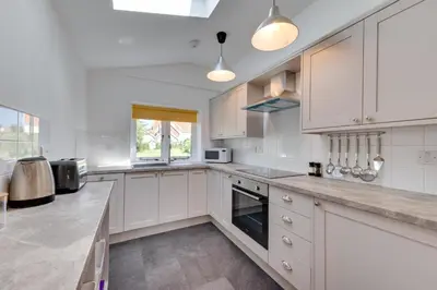 a white kitchen with white cabinets and a window at 1 Bed in Wenhaston oc-jap in Wenhaston
