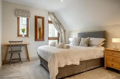 a bedroom with a large bed with a desk and a chair at 7 Bed in Aldeburgh oc-midba in Aldeburgh