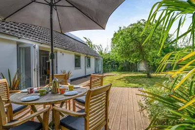 a wooden deck with a table and chairs with an umbrella at 3 Bed in Westleton oc-egv in Westleton