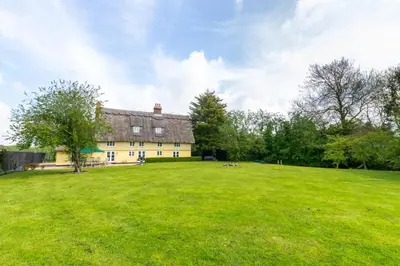 a large green field with a large yellow house at 5 Bed in Finningham oc-obhf in Finningham