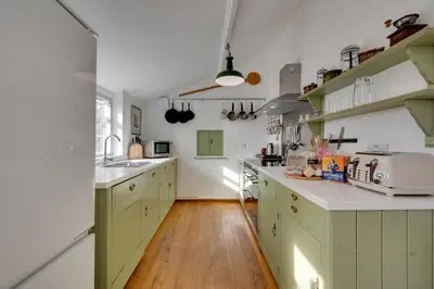 a kitchen with green cabinets and a wooden floor at 4 Bed in Orford oc-obh2 in Orford