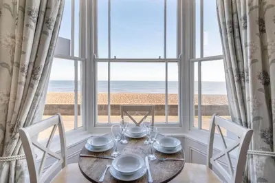 a dining room with a table and a view of the beach at 3 Bed in Aldeburgh oc-reg in Aldeburgh