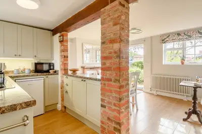 a kitchen with white cabinets and a brick pillar at 2 Bed in Saxmundham oc-rvr in Snape