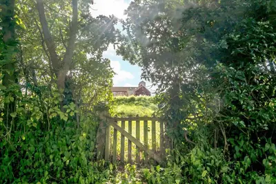 a wooden fence in a garden with a house in the background at 2 Bed in Saxmundham oc-rvr in Snape