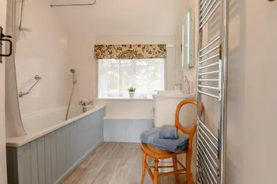 a bathroom with a tub and a sink and a chair at 2 Bed in Saxmundham oc-rvr in Snape