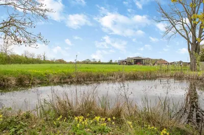 a pond in a field with a house in the background at 2 Bed in Otley oc-slm in Burgh