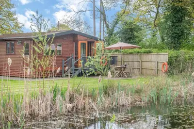 a wooden cabin with an umbrella next to a pond at 2 Bed in Otley oc-slm in Burgh