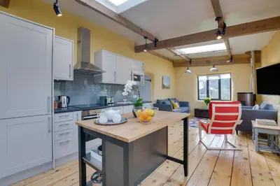 a kitchen and living room with white cabinets and a table at 2 Bed in Haughley oc-strb in Haughley