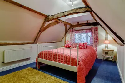a bedroom with a red bed in a attic at 5 Bed in Metfield oc-stfarm in Metfield