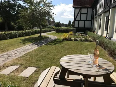 a wooden table with a bottle of wine and two glasses at 4 Bed in Thorpeness oc-cho in Thorpeness