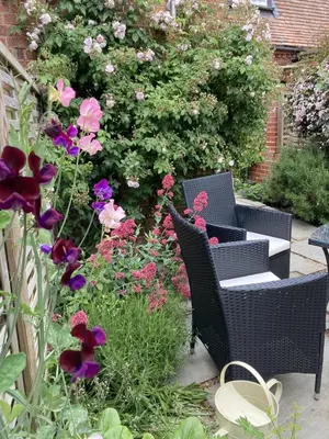 a garden with two wicker chairs and flowers at 2 Bed in Orford oc-sflpo in Orford