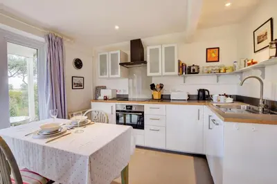 a kitchen with white cabinets and a table and a sink at 2 Bed in Snape oc-sfoms in Snape