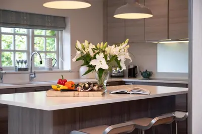 a kitchen counter with a vase of flowers and a book at 5 Bed in Orford oc-pav in Orford